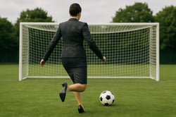 a business woman viewed from the rear preparing to kick a soccer ball into goal